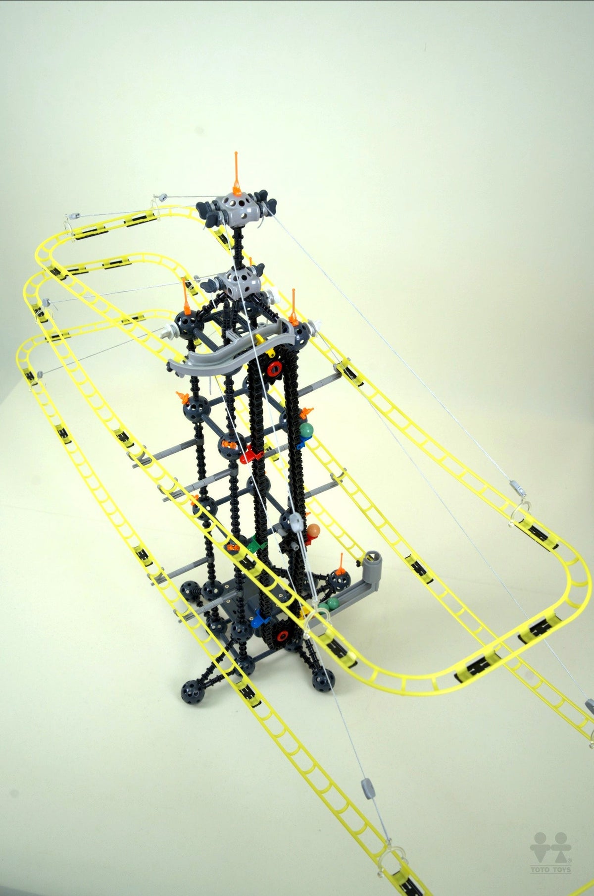 Fly Bridge tower angled on a cream background, black lattice frame with yellow looping tracks