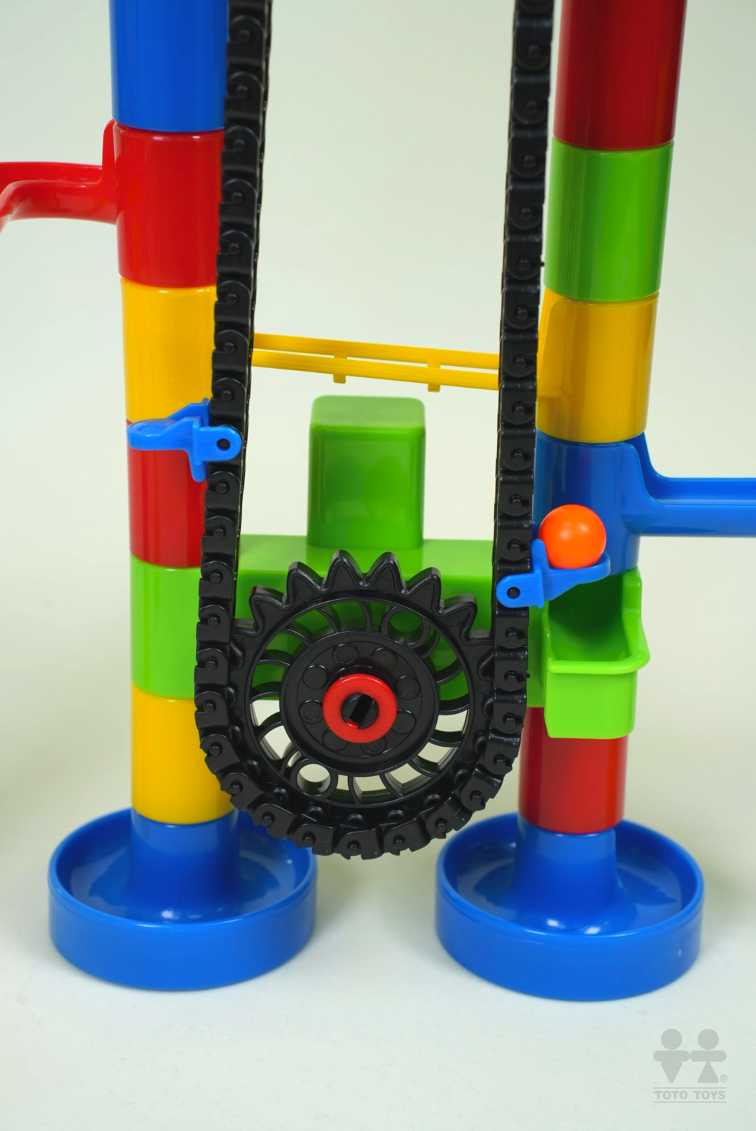 Close-up of the AutoRun chain and red gear mechanism with rainbow striped pillars and a marble