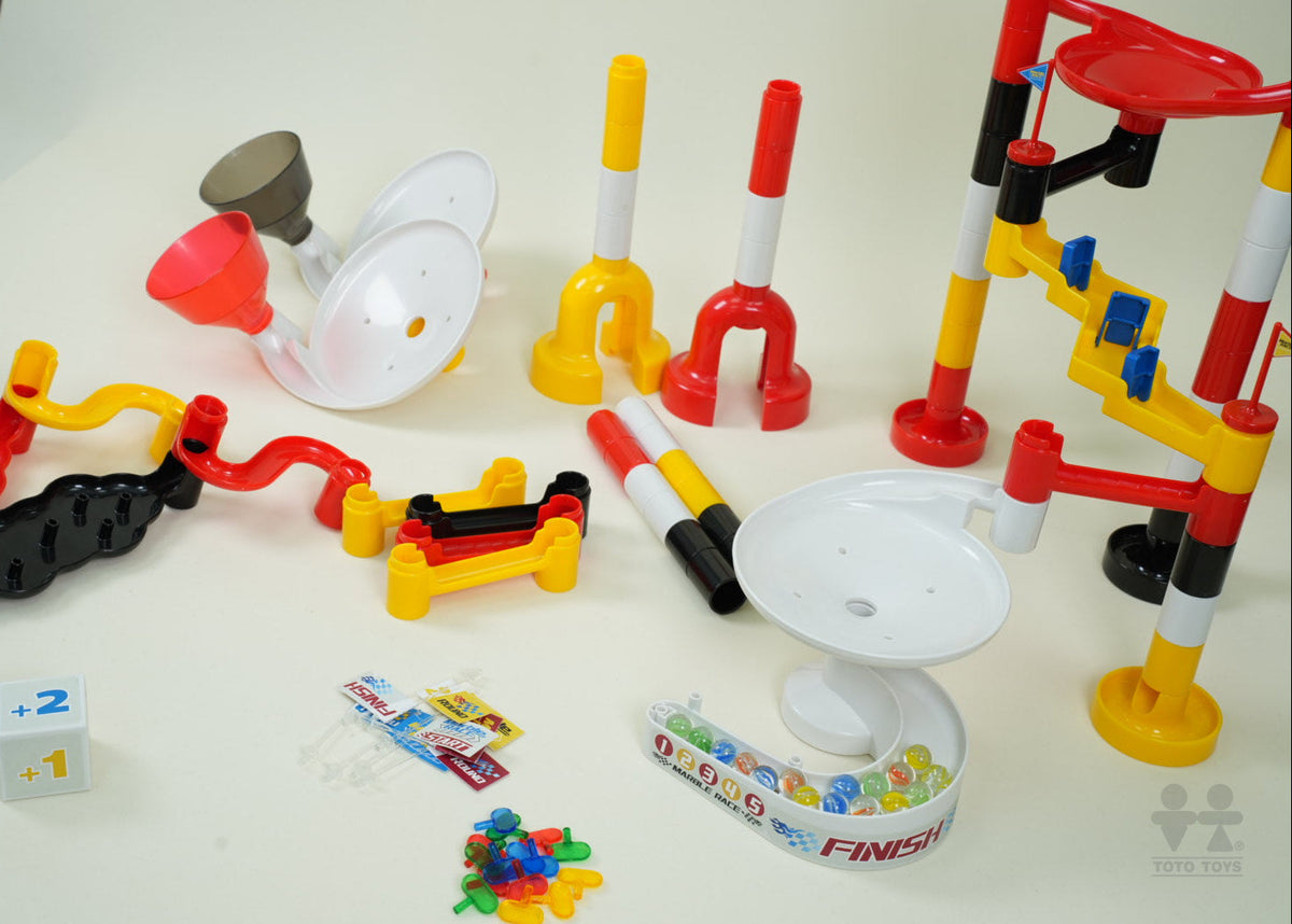 Marbulous racing set parts laid out: funnels, striped posts, track pieces, +1/+2 dice and printed FINISH tray